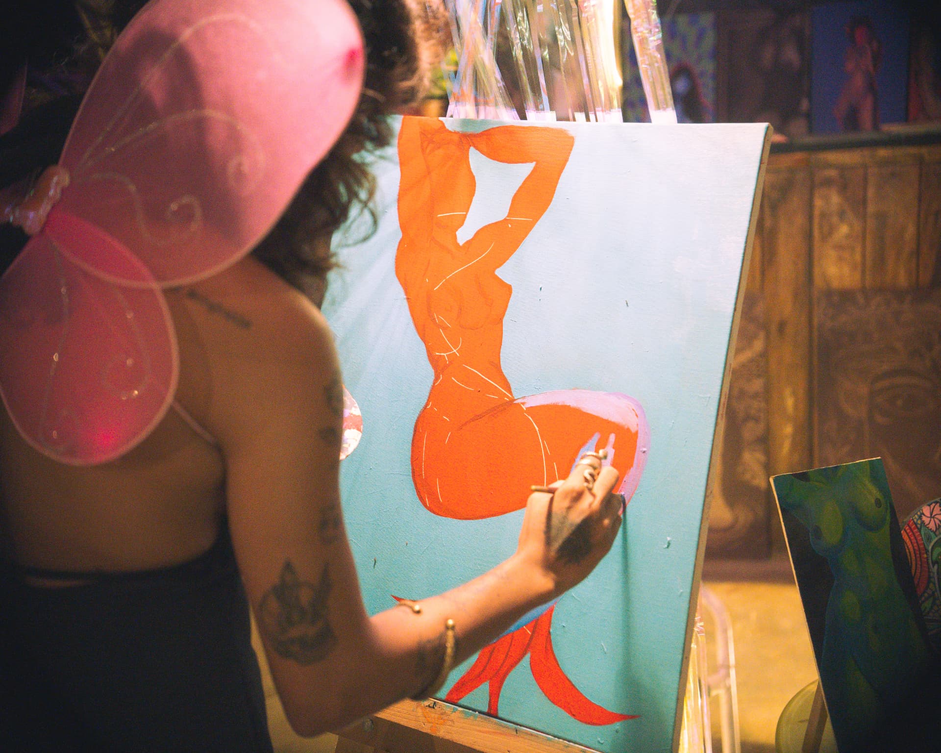 Orange figure painting taking shape on a turquoise canvas
