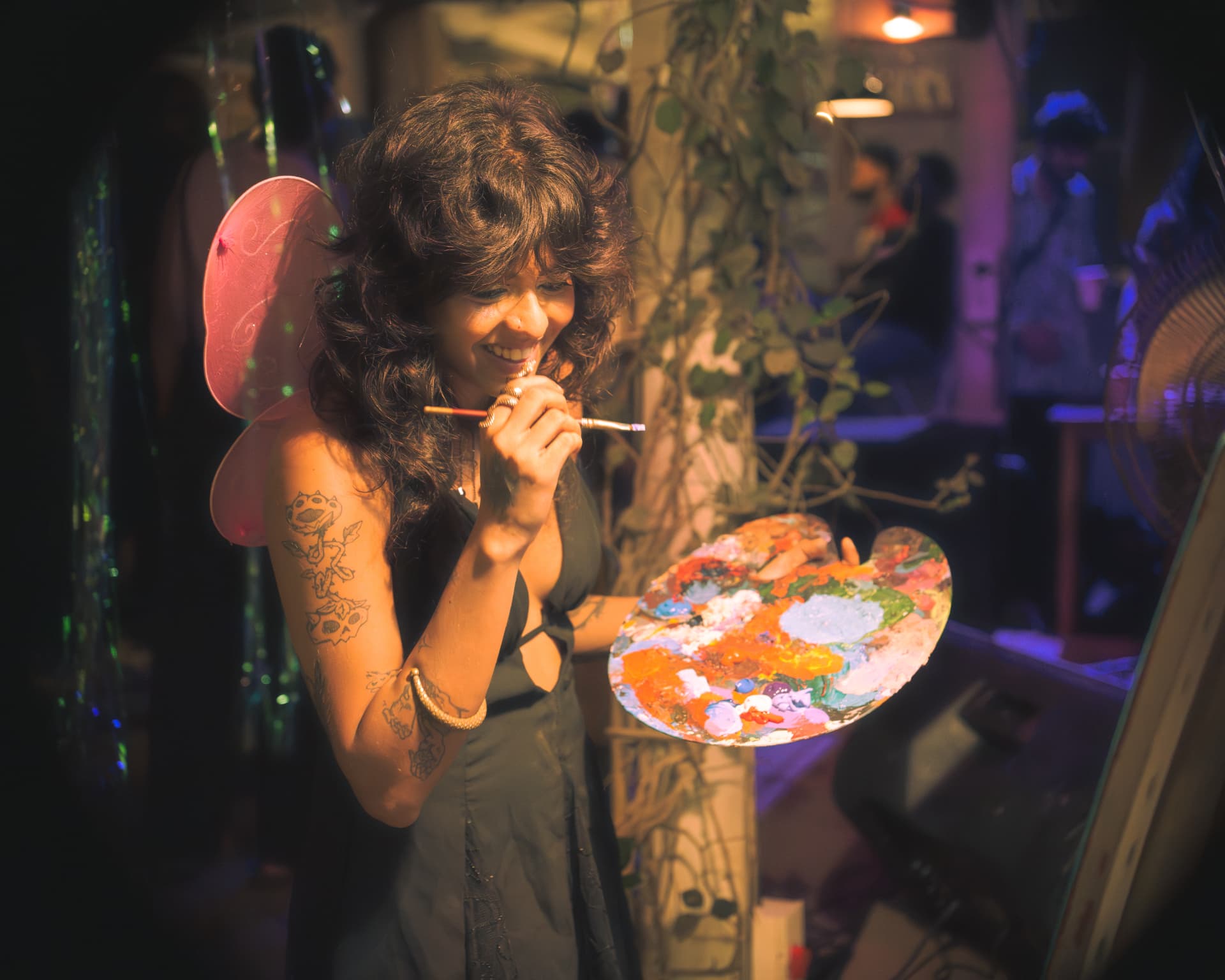 Live artist painting with fairy wings under warm stage light