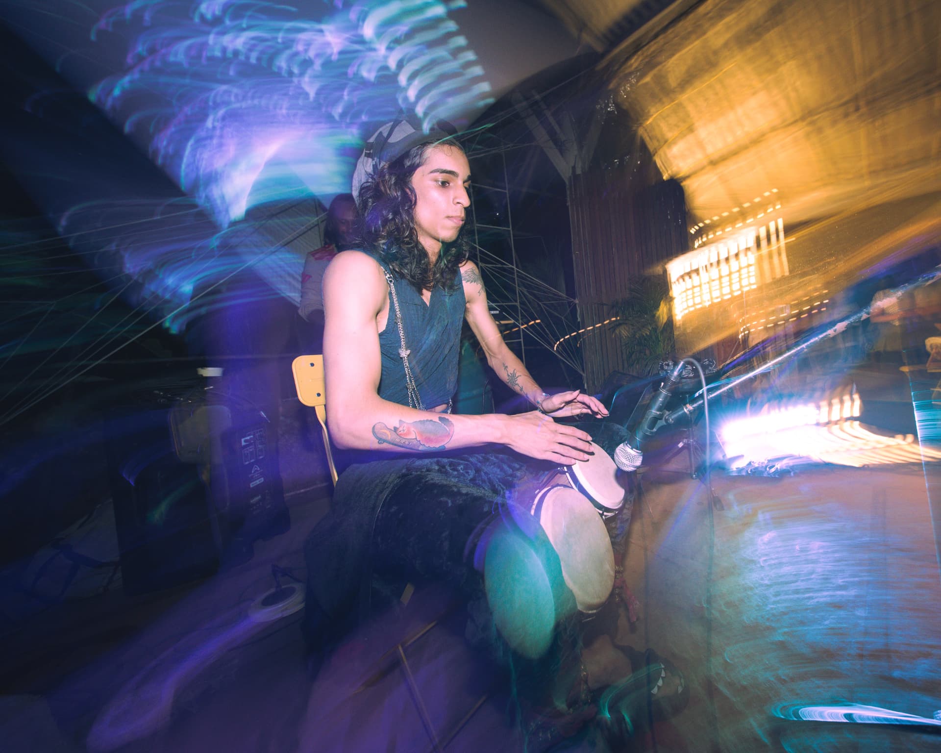 Percussionist playing djembe amid streaks of coloured light