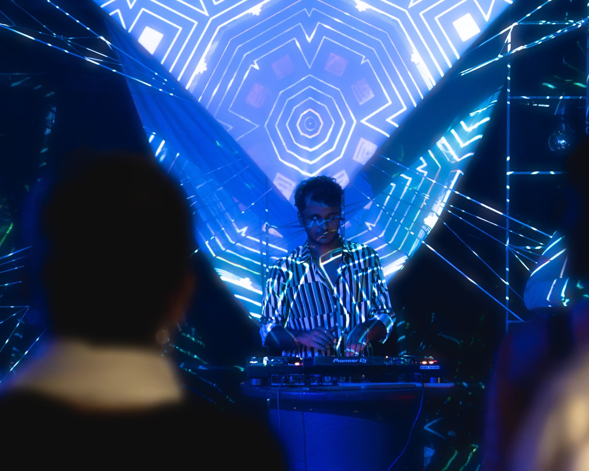 DJ playing beneath a kaleidoscopic blue projection