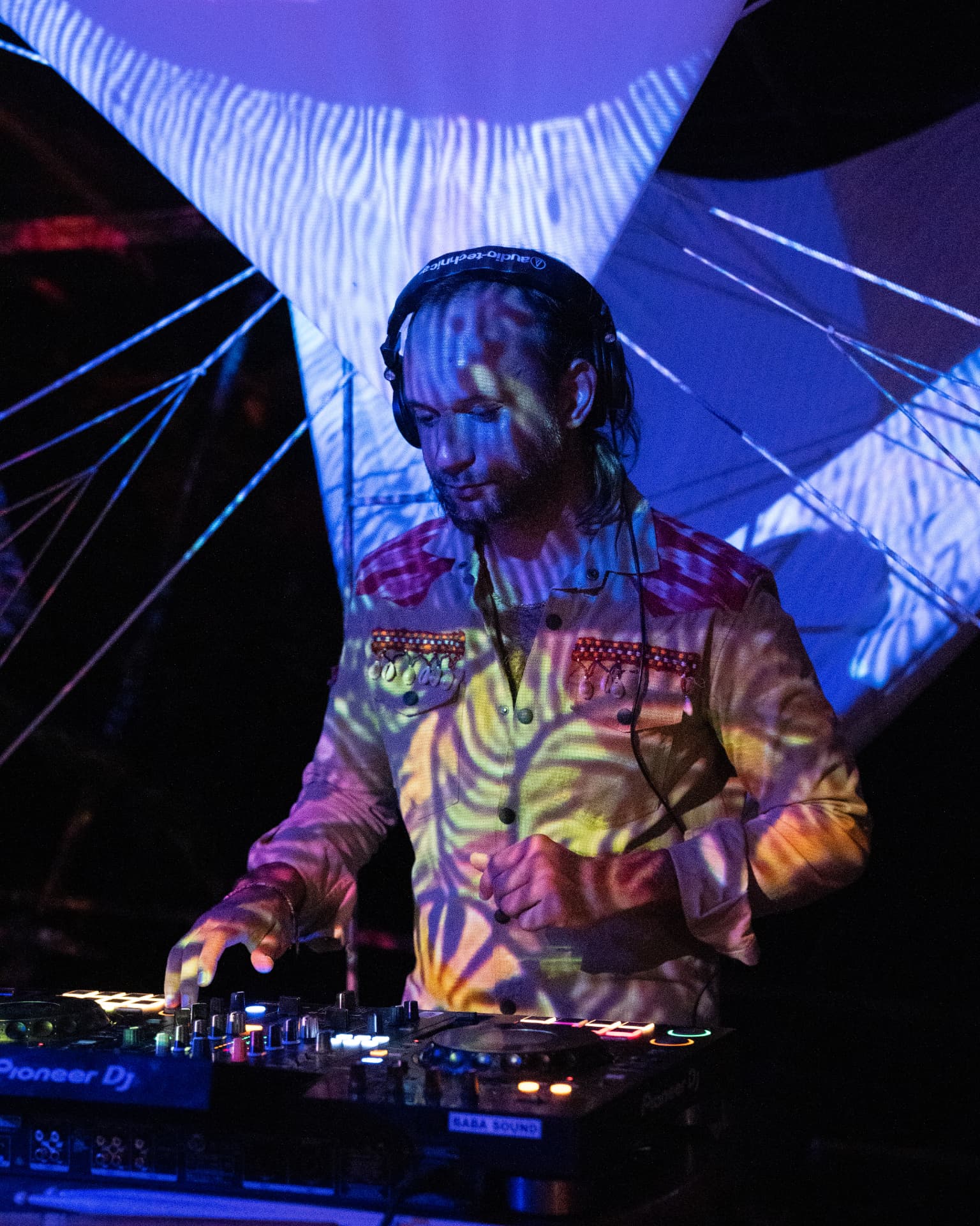 DJ in headphones washed in patterned projection light