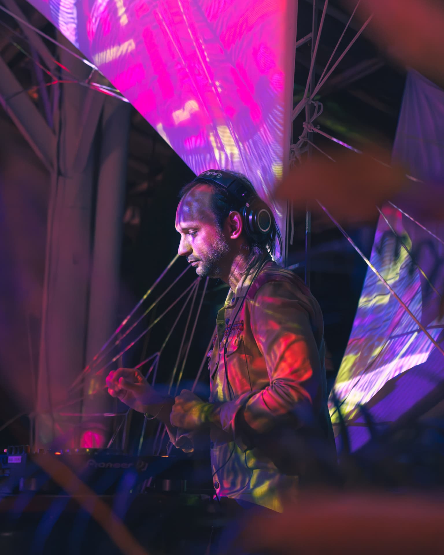 DJ in profile against pink and violet projection screens