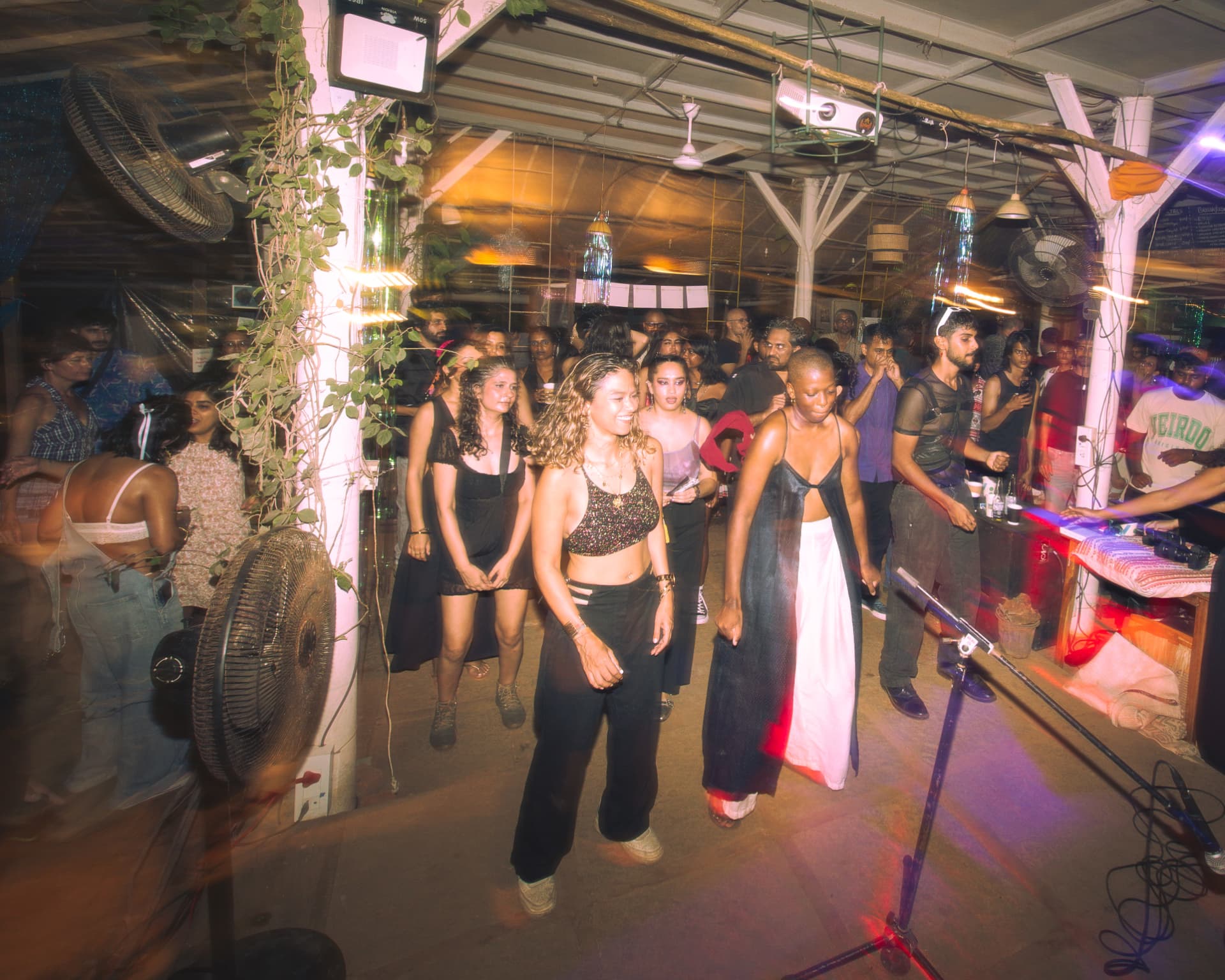 Crowd dancing across the venue floor in warm light