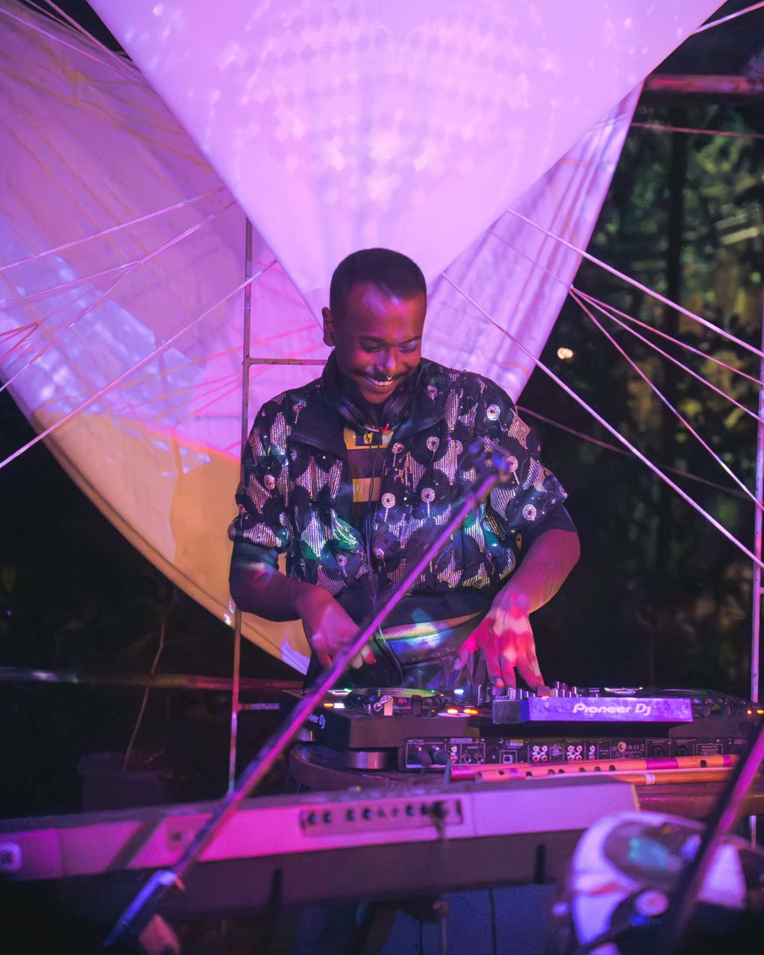 DJ smiling behind the decks in pink light