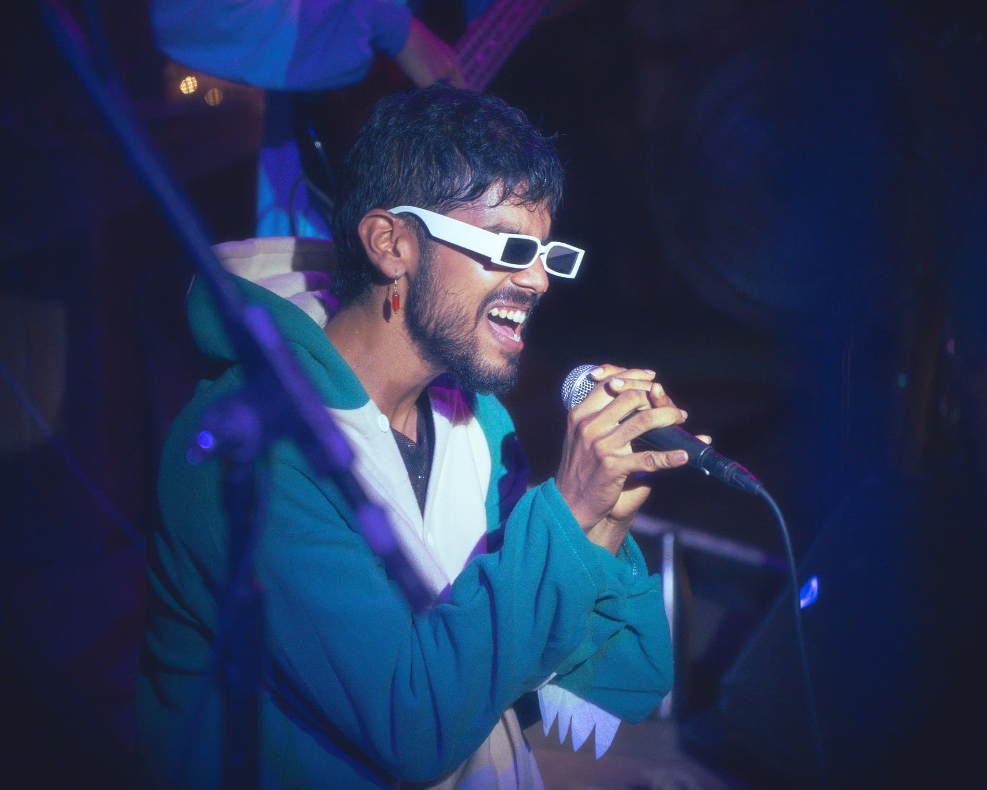 Singer with white sunglasses performing into a microphone