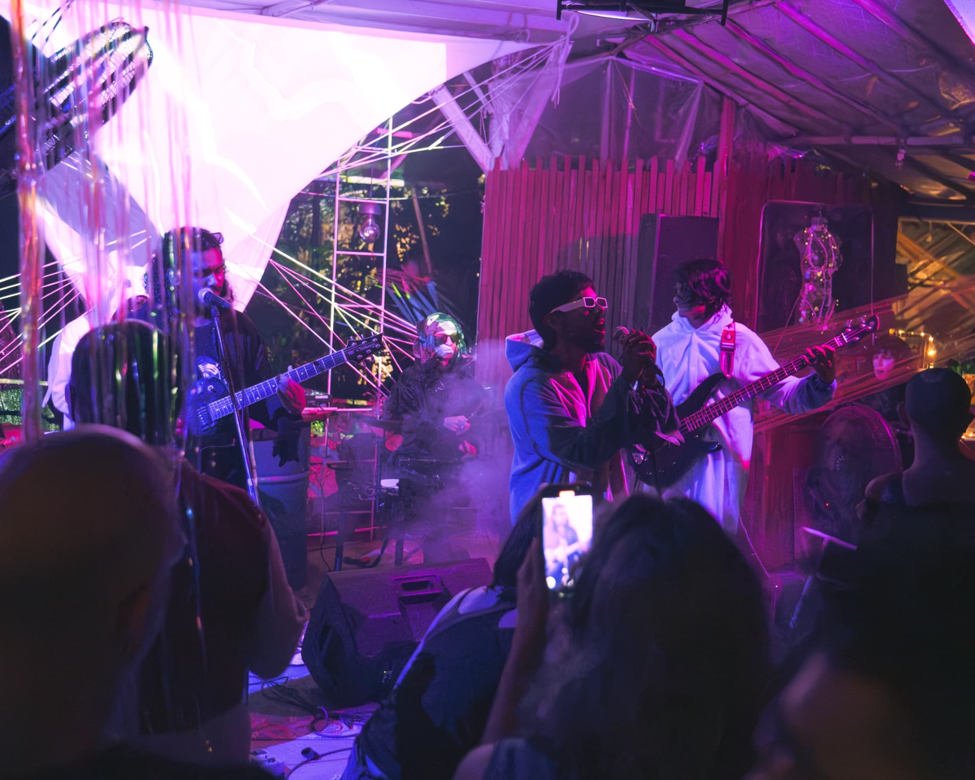 Band performing to a crowd under pink and violet lights